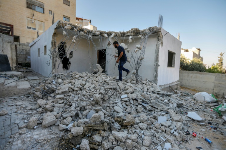 Palestinian walking on rubble of demolished East Jerusalem home