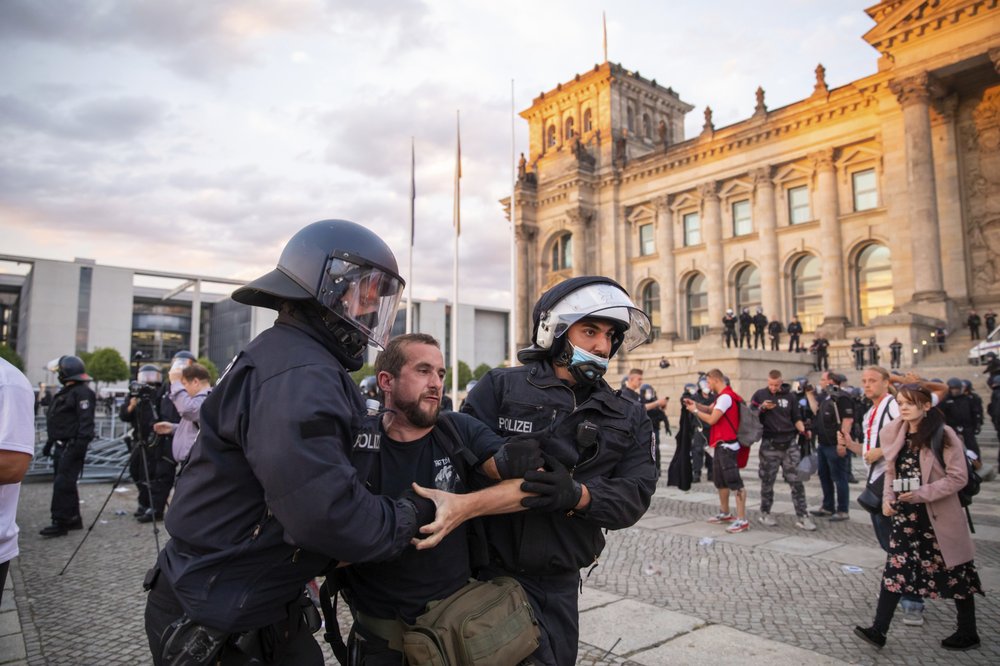 Police officers push away a crowd of demonstrators from the square 'Platz der Republik' in front of the Reichstag building during a demonstration against the Corona measures in Berlin, Germany 