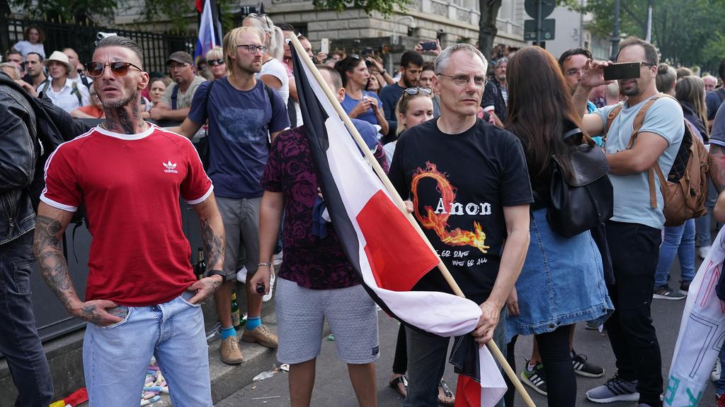 Mostly right-wing protesters, including a man wearing a QAnon shirt, face off against riot police on Unter den Linden avenue during protests against coronavirus-related restrictions