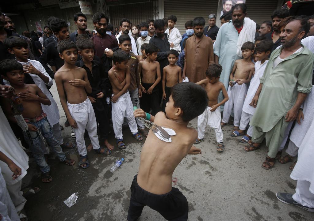 A Shiite Muslim boy flagellates himself with knifes on chains to show his grief during a procession marking Ashoura, in Lahore, Pakistan 