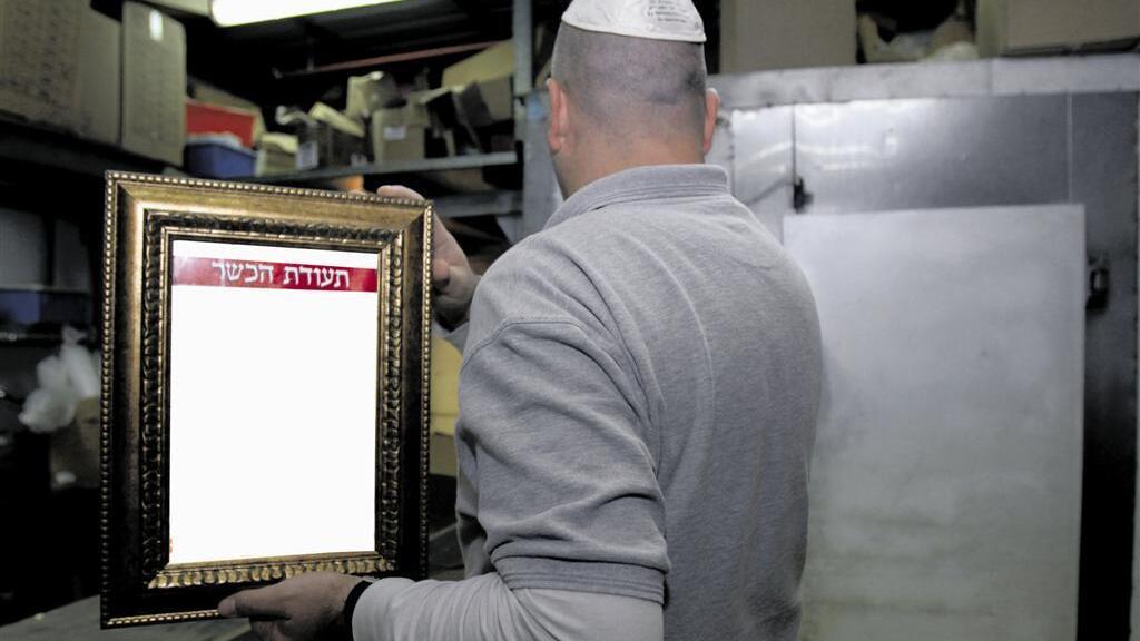 An Israeli business owner holding his kashrut certificate 