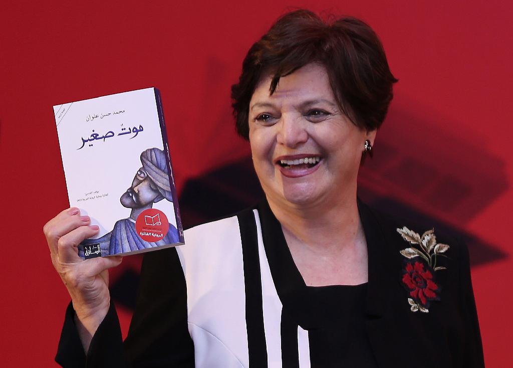 Sahar Khalifeh chair of the Arab fiction judges announces the winning writer, Mohammed Hasan Alwan, Saudi Arabia’s novelist, as she shows his book, A Small Death, during the International Prize for Arabic Fiction (IPAF) in Abu Dhabi, United Arab Emirates 