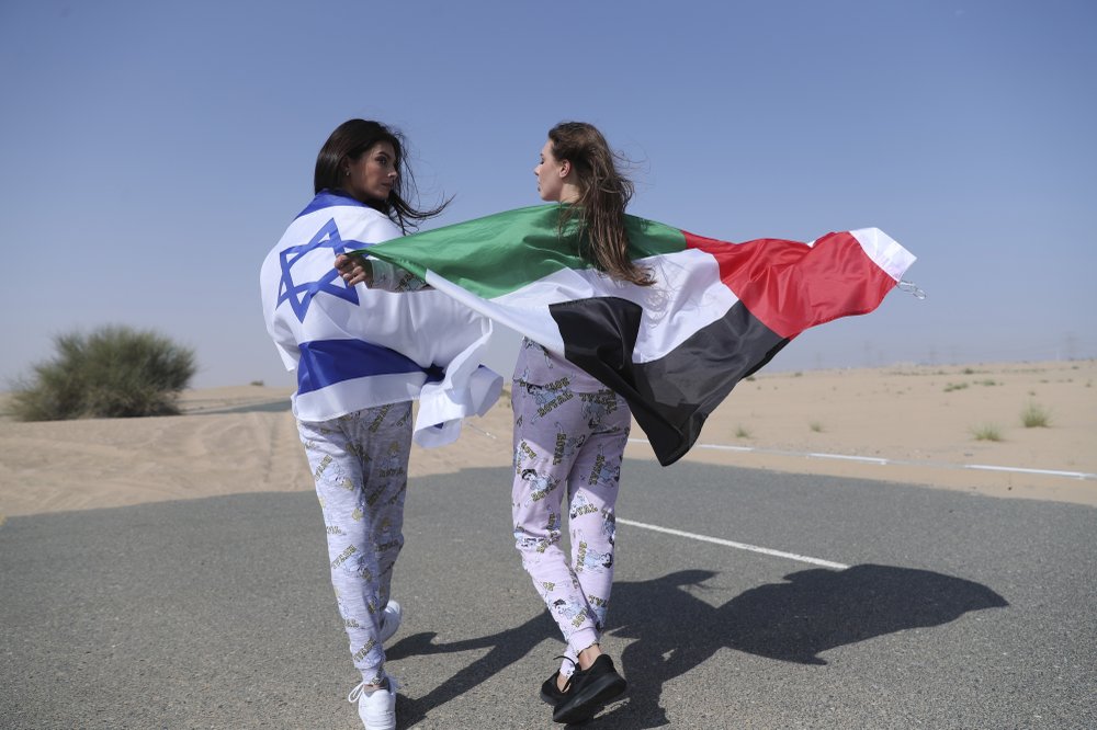 Israeli model May Tager, left, covers herself with an Israeli flag next to Anastasia Bandarenka, a Dubai-based model who wraps herself in a UAE flag during a photo shoot in Dubai, United Arab Emirates 