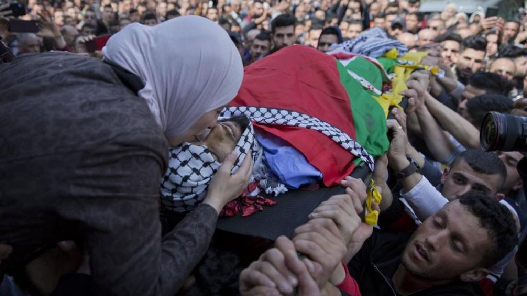  Wafa Manasra, mother of Palestinian Ahmad Manasra, kisses him goodbye during his funeral in the West Bank village of Wad Fokin, near Bethlehem