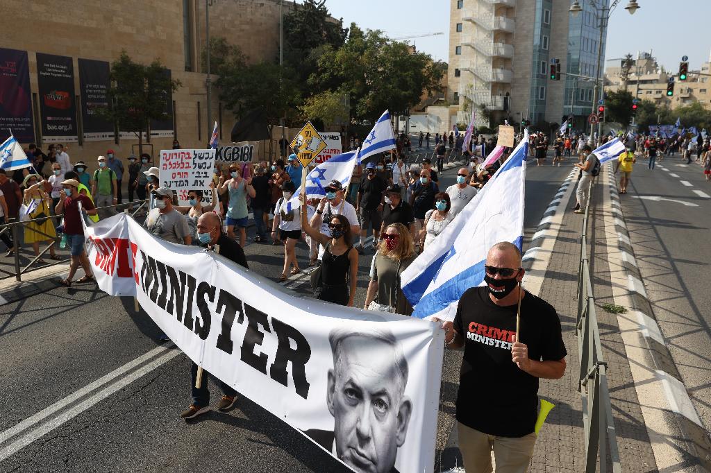 Anti-Netanyahu protesters march with sign calling him 'Crime Minister' near residence in Jerusalem on Saturday 
