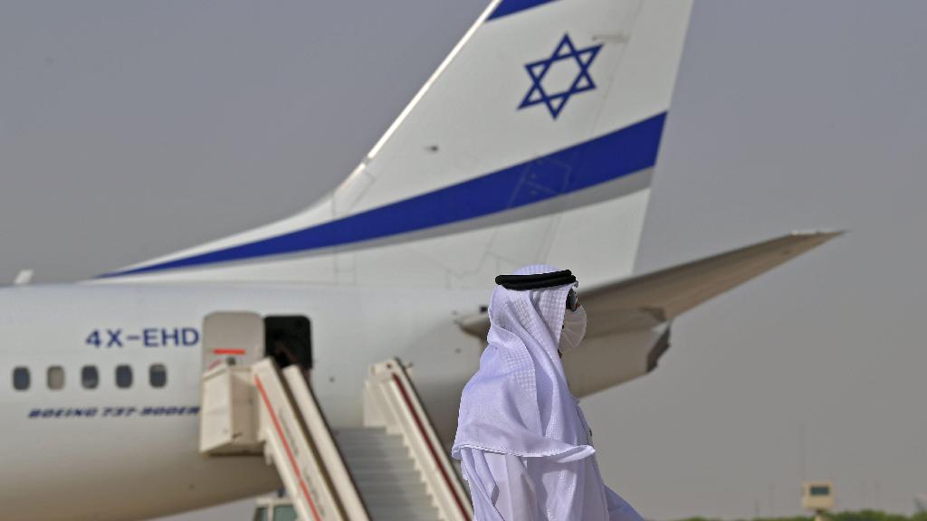 An Emirati official stands near an air-plane of El Al, which carried a US-Israeli delegation to the UAE following a normalisation accord, upon it's arrival at the Abu Dhabi airport