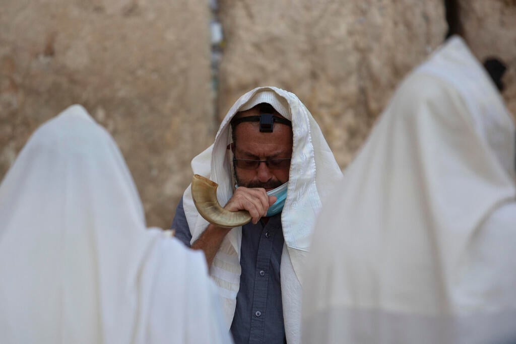 An ultra-Orthodox Jewish man blows a shofar, a musical instrument made from an animal horn, as he prays ahead of the Jewish new year at the Western Wall