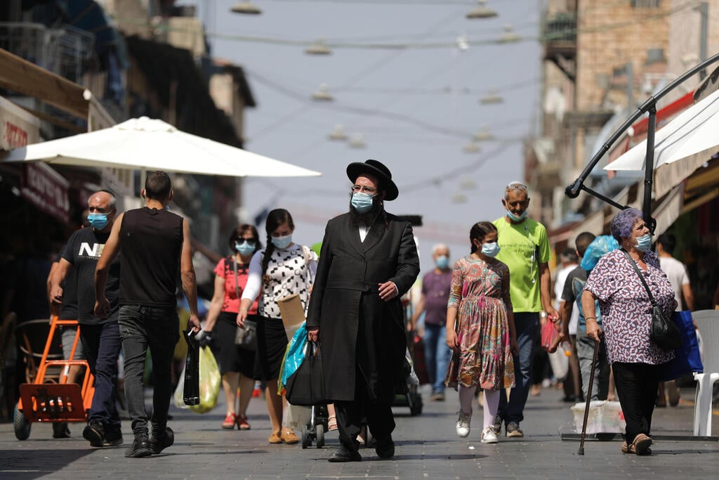 People wearing protective face masks shop at the Mahane Yehuda market ahead of the Rosh Hashana holiday lockdown in Jerusalem