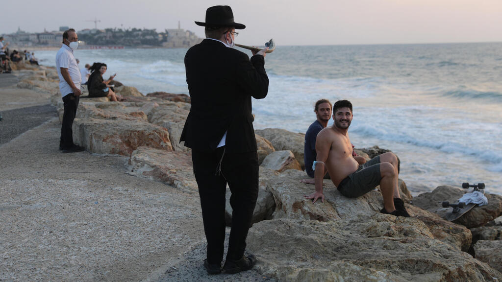 An Orthodox Jewish man blows the shofar as he performs a Tashlich Prayer at the beach during lockdown at the Jewish holiday of Rosh Hashanah in Tel Aviv