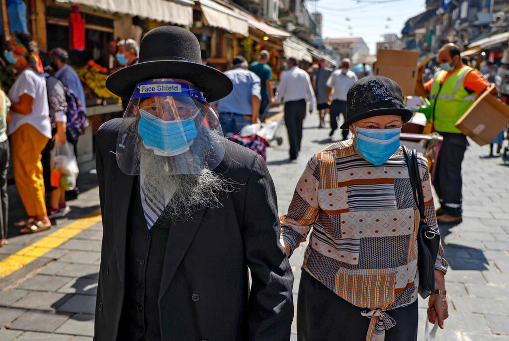 An Israeli couple wears face masks during a visit to Mahane Yehuda market in Jerusalem 