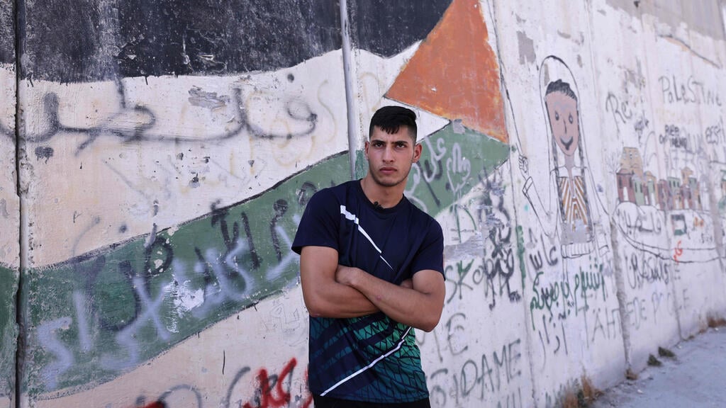 Palestinian student at Al-Quds University Moayad Afaneh, 22, poses for a picture during an interview with AFP by the wall separating East Jerusalem from the Palestinian village of Abu Dis 