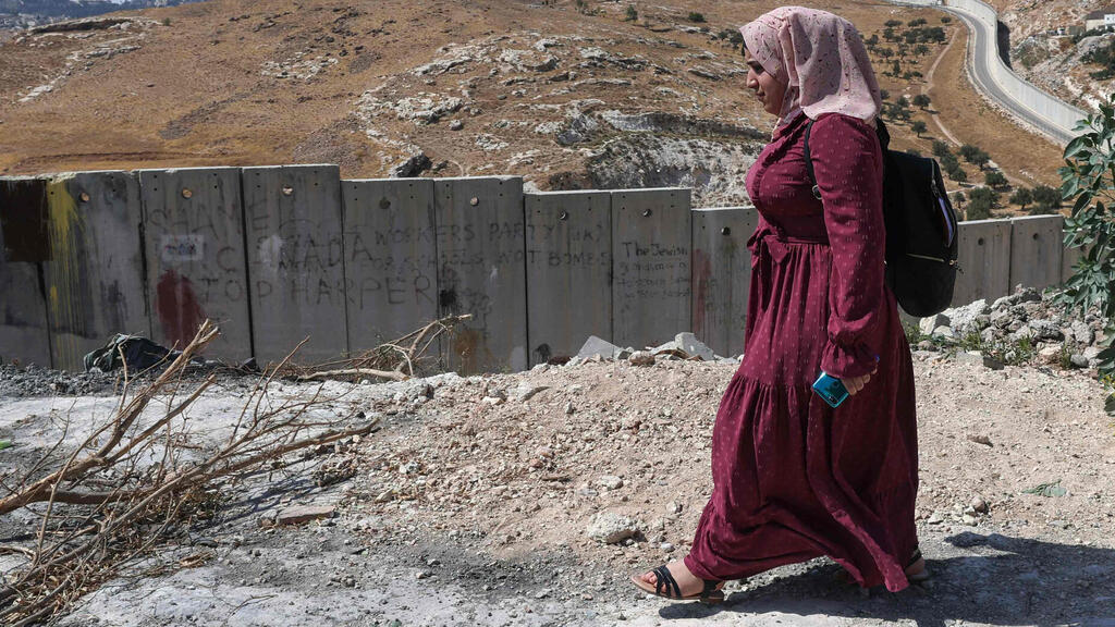 Palestinian student at Al-Quds University Aya Abu al-Amal, 18, makes her way to class along the wall separating East Jerusalem from the Palestinian village of Abu Dis 