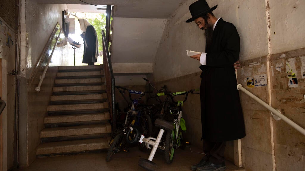 Ultra-Orthodox Jews keep social distancing and wear face masks during a morning prayer next to their houses as synagogues are limited to twenty people due to the coronavirus pandemic, in Bnei Brak 