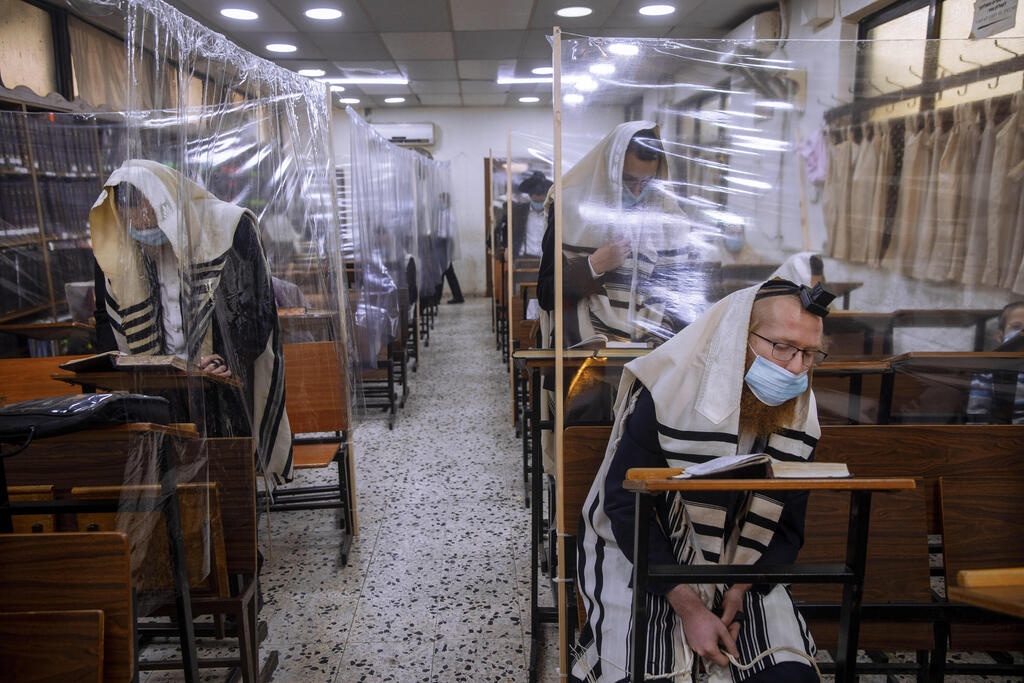  In this Monday, Sept 21, 2020 file photo, ultra-Orthodox Jews wear face masks during a morning prayer in a synagogue separated by plastic partitions, in Bnei Brak 