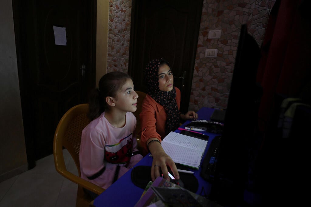 Palestinian sisters Raseel and Mariam Hussein attend their online lessons in their home, amid the coronavirus disease (COVID-19) outbreak, in Gaza City 