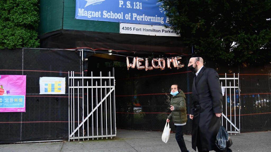 Hasidic males with facemasks, walk past a closed public school in the Brooklyn neighborhood of Borough Park 