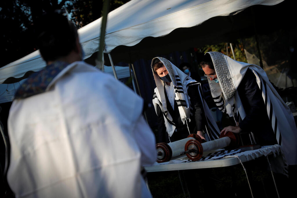 Men read from the Torah as Orthodox Jews gather for "Hoshanot prayers" as part of their Sukkot observance on a neighborhood lawn to avoid over-crowding at an indoor synagogue, following the outbreak of the coronavirus disease (COVID-19) in the New York City suburb of Monsey 
