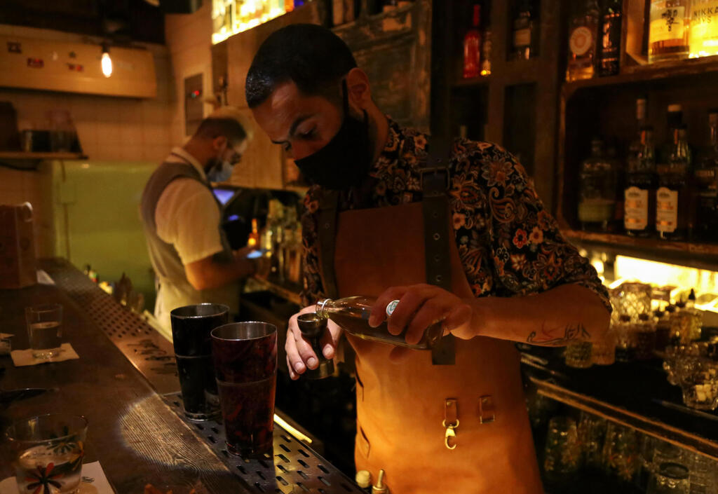 A bartender wearing a protective face mask prepares an alcoholic drink at a bar, amid concerns over the spread of the coronavirus disease (COVID-19), in Beirut, Lebanon 