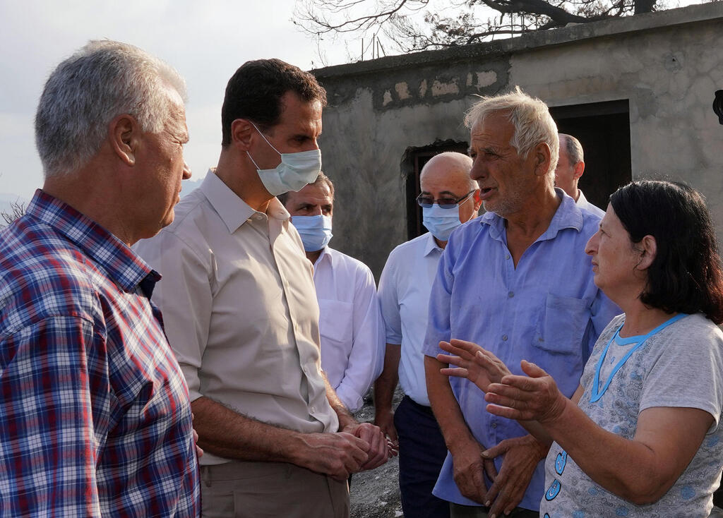 Syrian President Bashar Assad, second from left, wearing a mask to help prevent the spread of the coronavirus, speaks with people during his visit to the coastal province of Latakia 