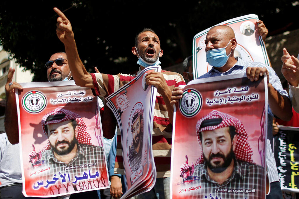 Demonstrators hold pictures of hunger-striking Palestinian prisoner Maher Al-Akhras, who is held by Israel, during a rally to show solidarity with Al-Akhras, in Gaza City 