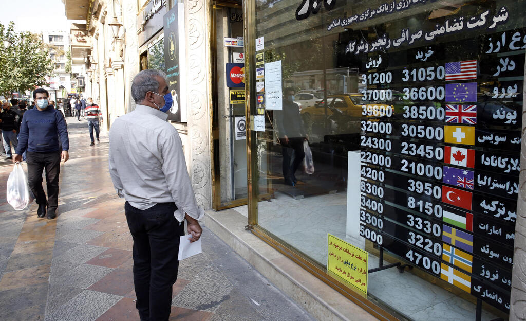 n Iranian man checks the currency rate as he walks past a currency exchange service in Tehran, Iran,