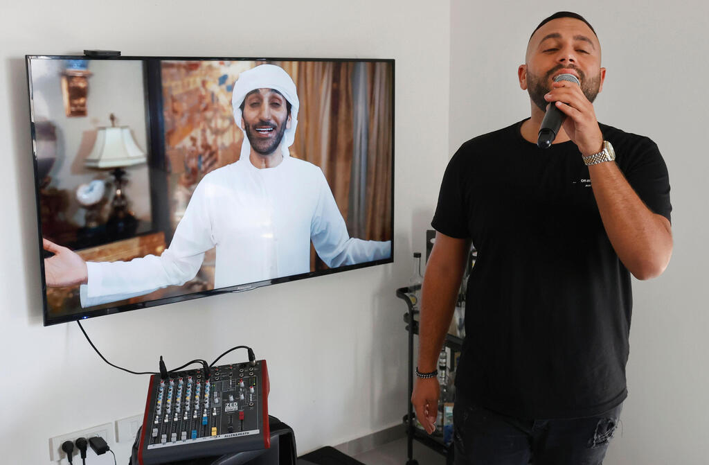 Israeli singer Elkana Marziano, 28, sings along with a video clip of a song on which he worked in collaboration with Emirati artist Walid Aljasim (image on screen) 