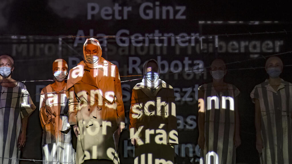 Names of victims scroll on a mesh at the Jewish State Theatre as actresses perform wearing face masks for protection against COVID-19 infection, during the rehearsals for premiere of the "The Beautiful Days of My Youth"