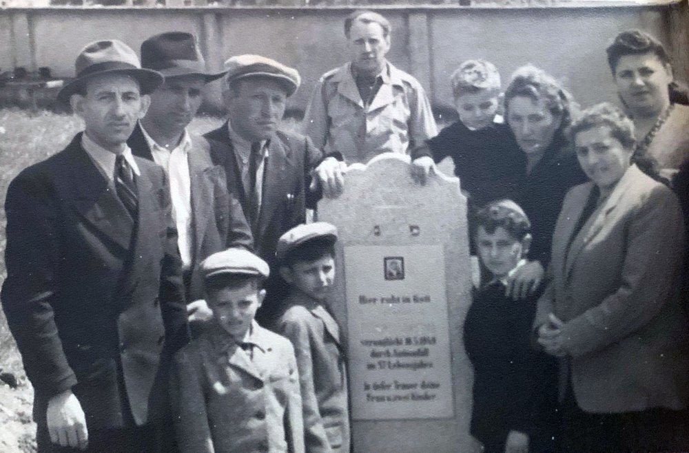 The Eisenberg and Brandspiegel families gather around the tombstone of Abraham Eisenberg at the Hallein Displaced Persons Camp in Austria in June 1948 