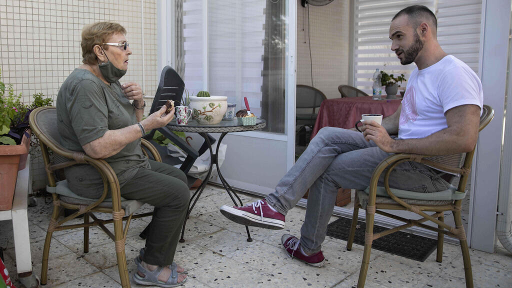 Israeli volunteer Sharon Yaron, left, brings a cake to 85-year-old Holocaust survivor Sara Weinsten during a visit to her house in Yavne, Israel, Thursday, Oct. 8, 2020 