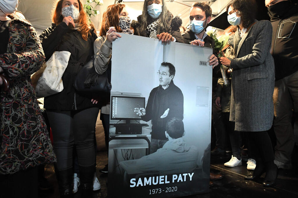 קרוביו ועמיתיו של ה מורה סמואל פאטי מחזיקים תמונה שלו בפרבר ליד פריז שבו נרצח ב פיגוע צרפת