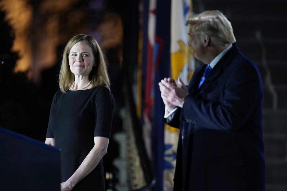 President Donald Trump looks toward Amy Coney Barrett, before Supreme Court Justice Clarence Thomas administers the Constitutional Oath to her on the South Lawn of the White House in Washington 