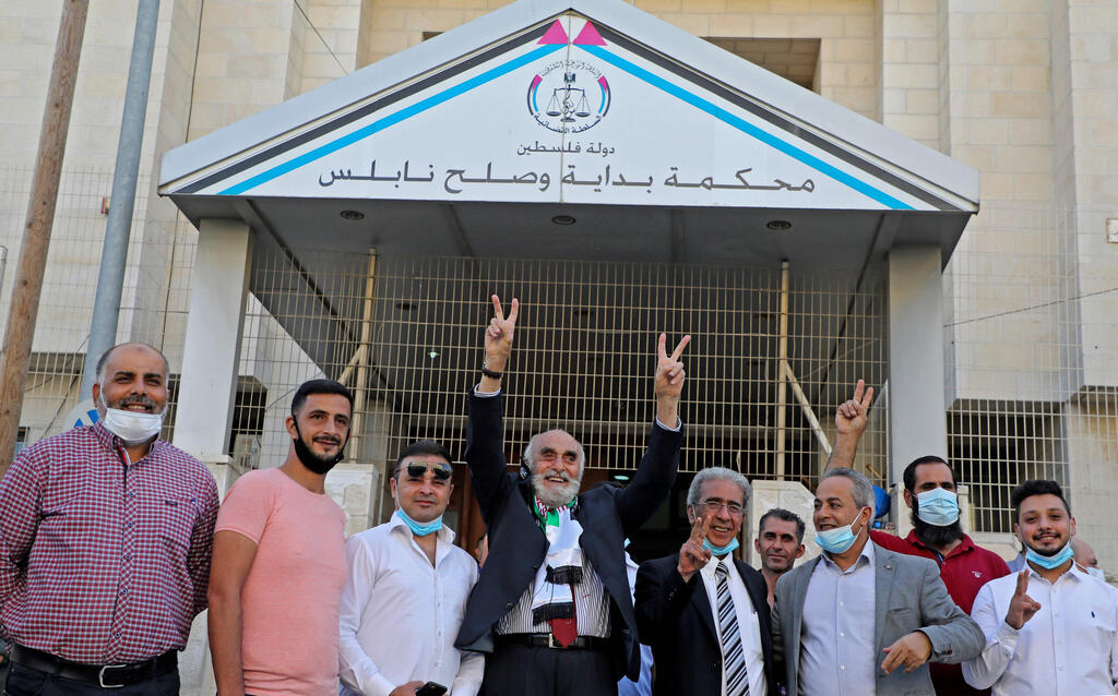Munib al-Masri, chief of the National Assembly of Independents, (C) flanked by activists gesture outside a court after filing a lawsuit against Britain over the 1917 Balfour Declaration that laid out a vision for a Jewish homeland in Palestine, in the West Bank city of Nablus 