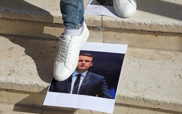 Stepping on the photograph of French President Emmanuel Macron in protest of his condemnation of Islamic extremism 