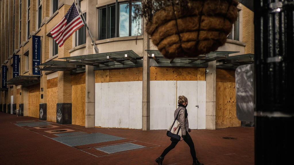  A woman passes by a store protected with wooden boards in Washington,
