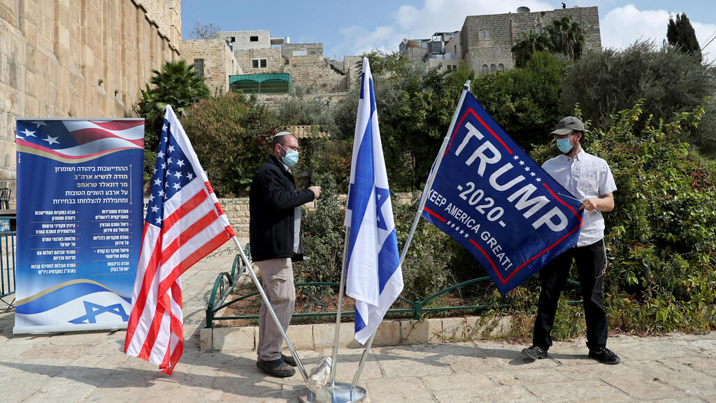 An Israeli settler adjusts a flag during a gathering to show support for U.S. President Donald Trump in the upcoming U.S. election, at the Cave of the Patriarchs, in the Palestinian city of Hebron
