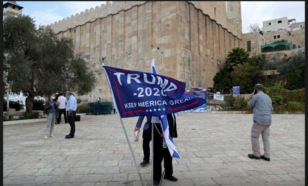 An Israeli settler adjusts a flag during a gathering to show support for U.S. President Donald Trump in the upcoming U.S. election, at the Cave of the Patriarchs, in the Palestinian city of Hebron
