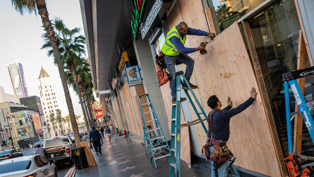 Workers from BluSky, an emergency services and restoration company, secure plywood to protect windows along Hollywood Boulevard on election day.