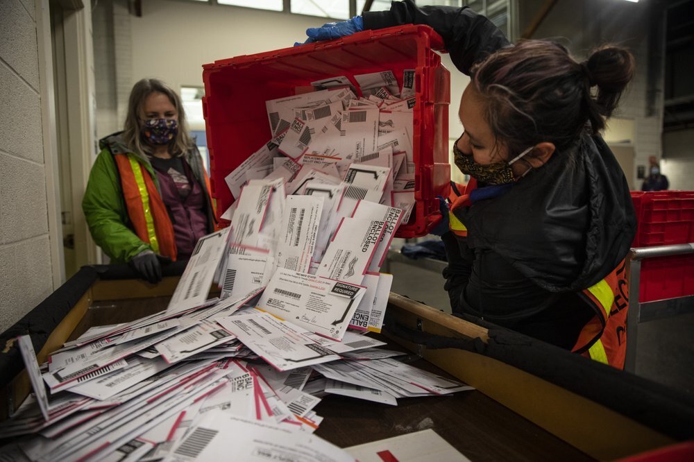 Election worker Kristen Mun from Portland empties ballots from a ballot box at the Multnomah County Elections Division, Tuesday, Nov. 3, 3030 in Portland, Ore. 