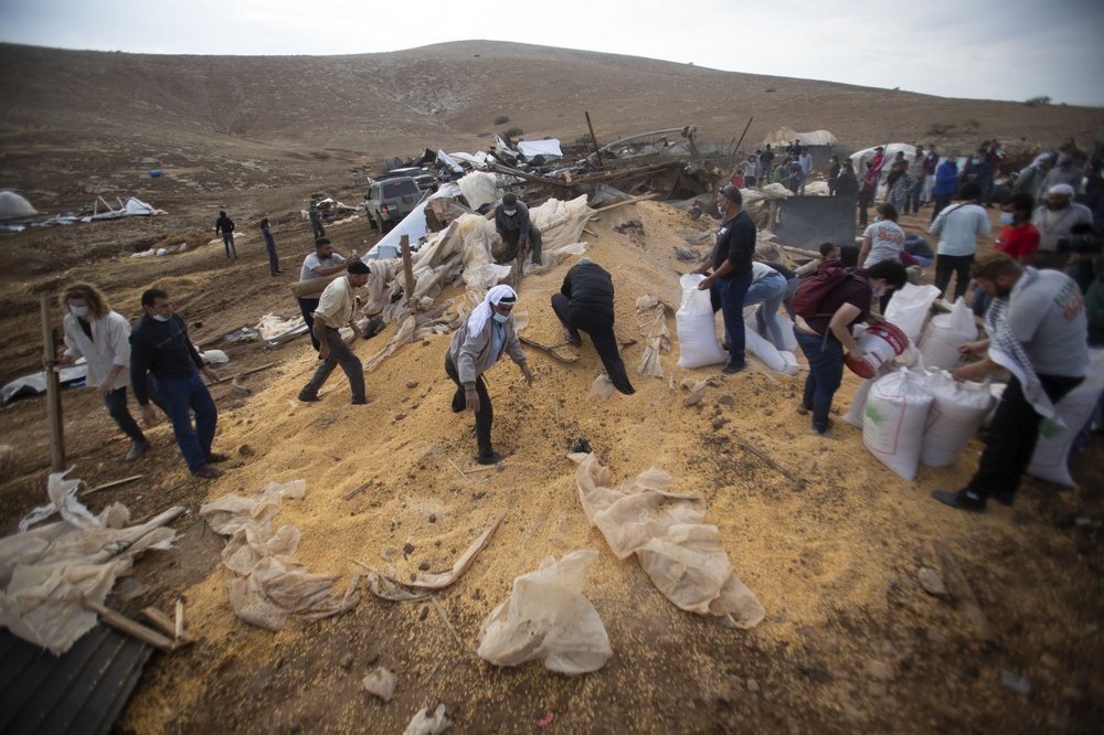 Palestinians collect grain aftre Israeli military destroyed storage structure n Khirbet Humsu in Jordan Valley in the West Bank