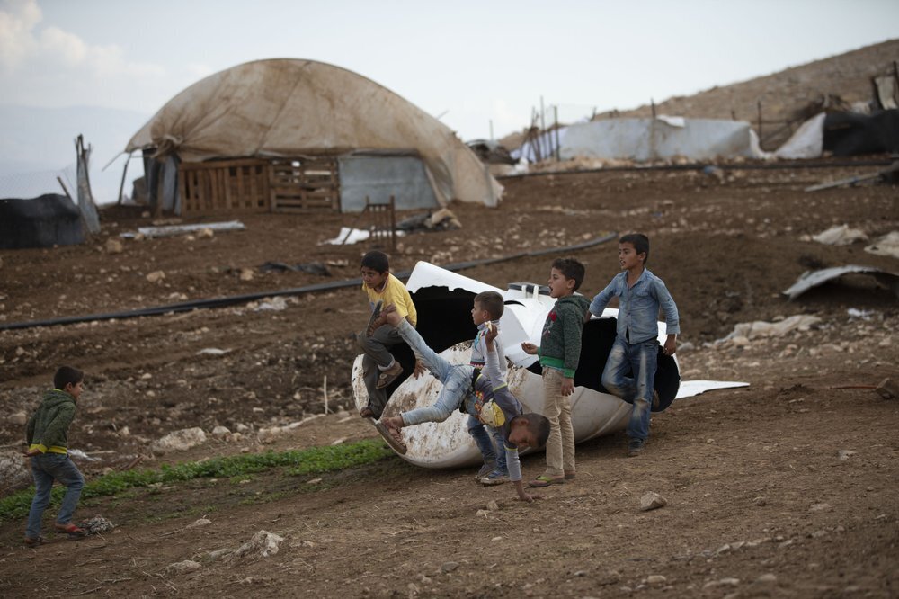 Palestinian children play by a destroyed tank in Khirbet Humsu in Jordan Valley in the West Bank