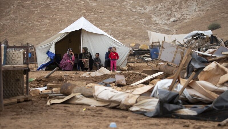 Palestinian women and children sit front a tent in Khirbet Humsu in Jordan Valley in the West Bank