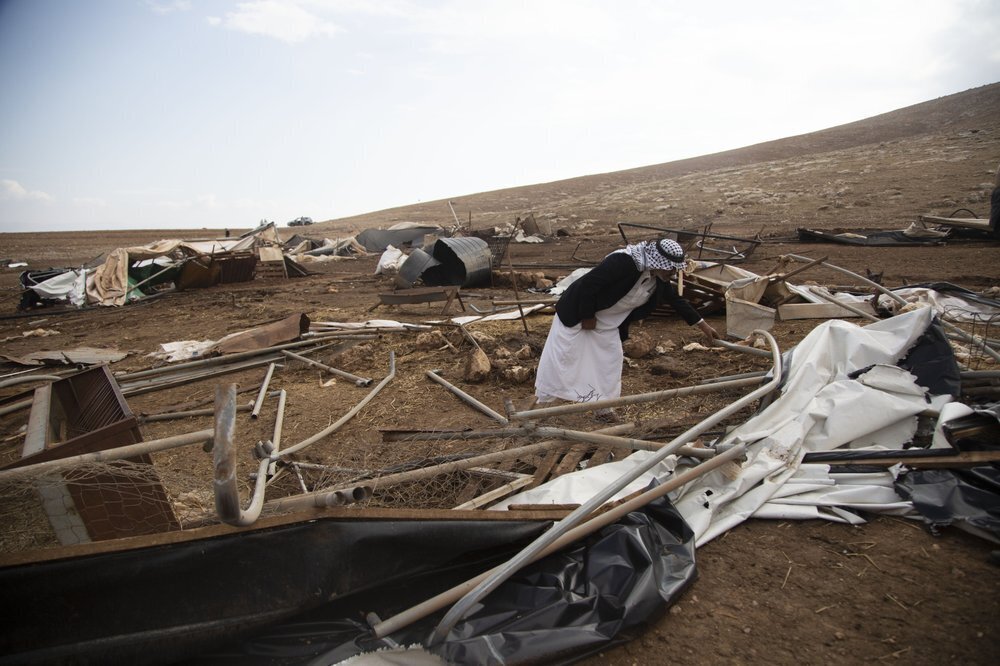 A Palestinian sifts through destroyed tents in Khirbet Humsu in Jordan Valley in the West Bank