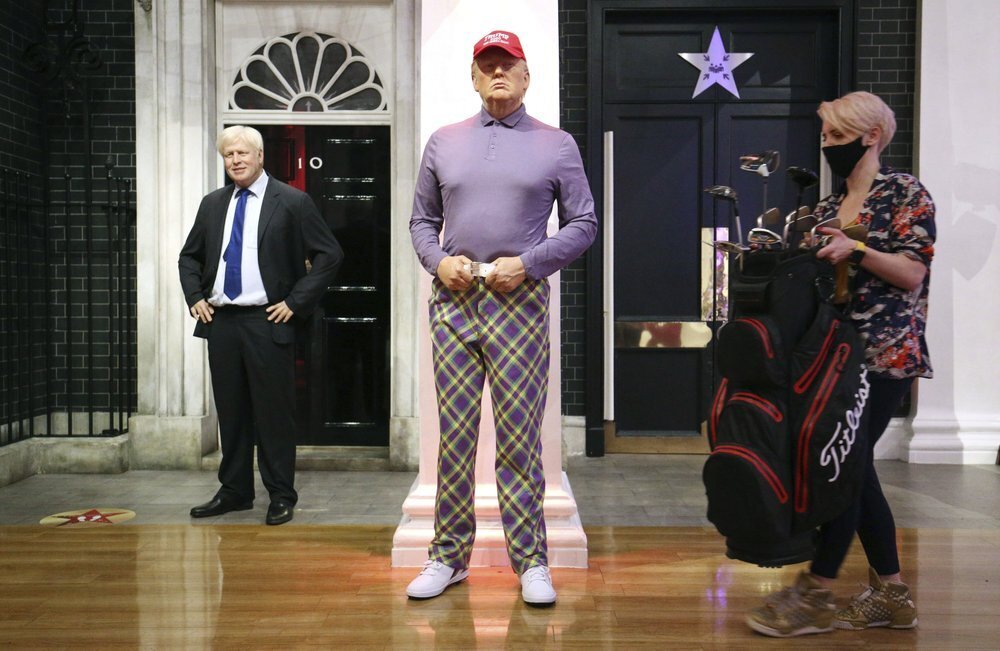 A member of the Madame Tussauds studios team places a set of golf clubs next to a wax figure of US President Donald Trump which has been re-dressed in golf wear following the 2020 US presidential election, in London 