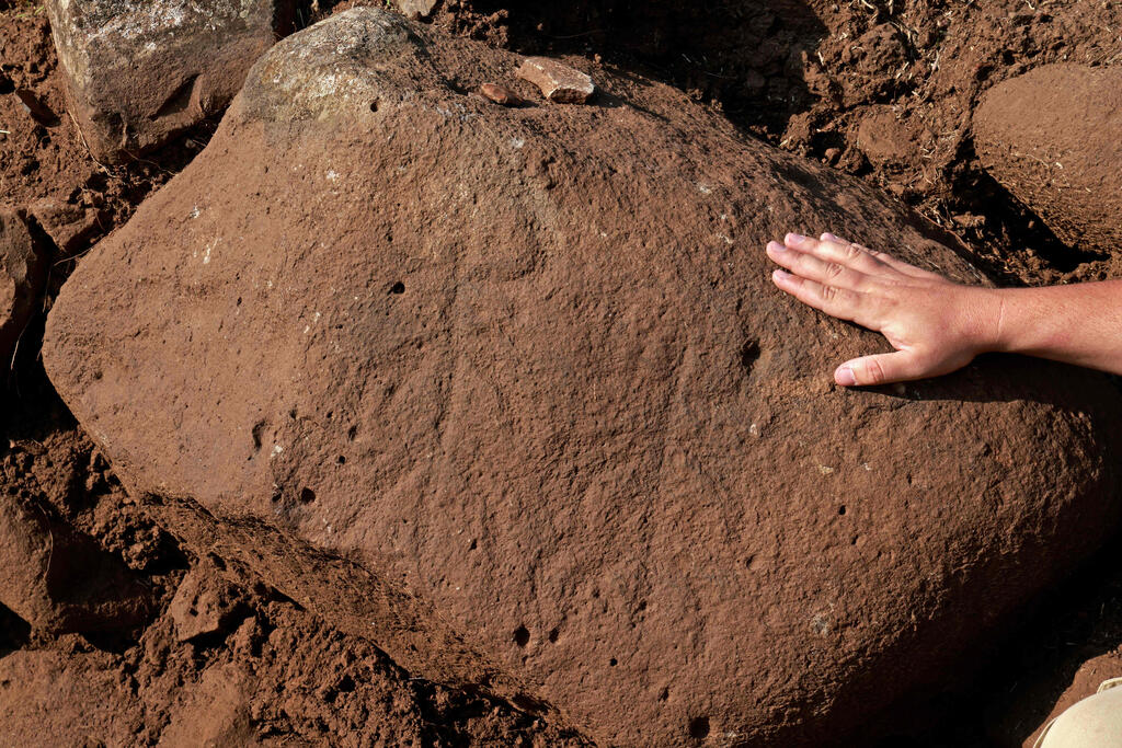 Barak Tzin, an Israel Antiquities Authority (IAA) archeologist, shows a rare engraved stone carved with two horned figures with outspread arms, at a fortified complex from the time of King David which was exposed for the first time in archaeological excavations carried out by IAA in the Hispin settlement in the Israeli-annexed Golan Heights 