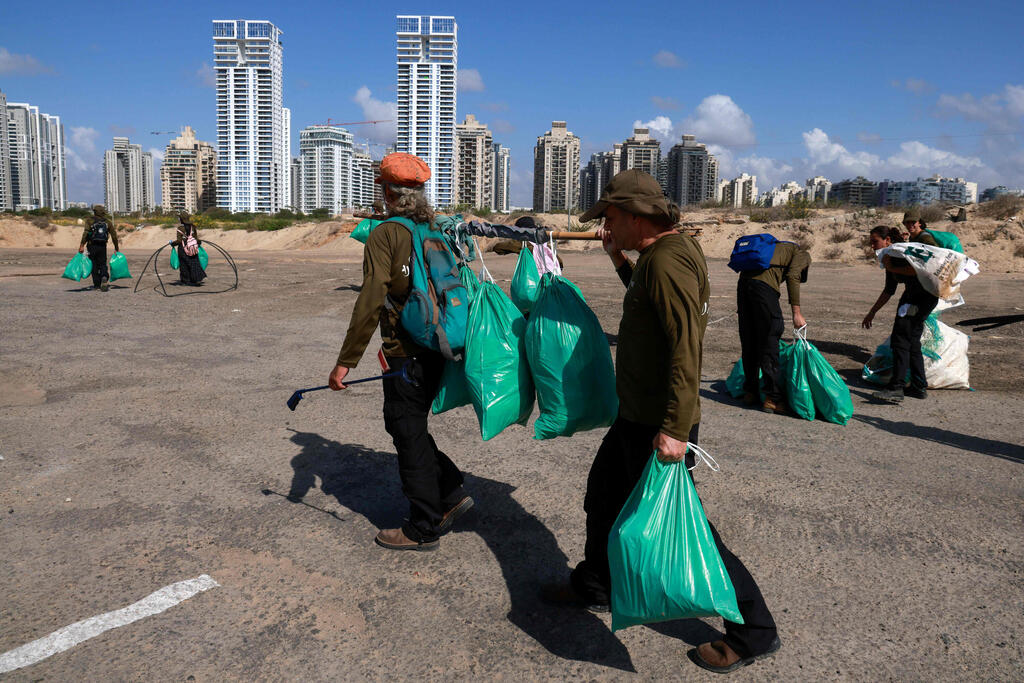 Israelis who lost their jobs due to Covid-19 coronavirus pandemic crisis, work on a new job collecting trash on the beach at the Peleg Nature reserve in the Mediterranean coastal city of Netanya 