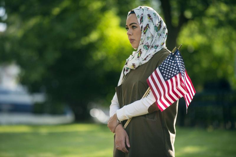 An Arab woman holds American flags in Flint, Michigan