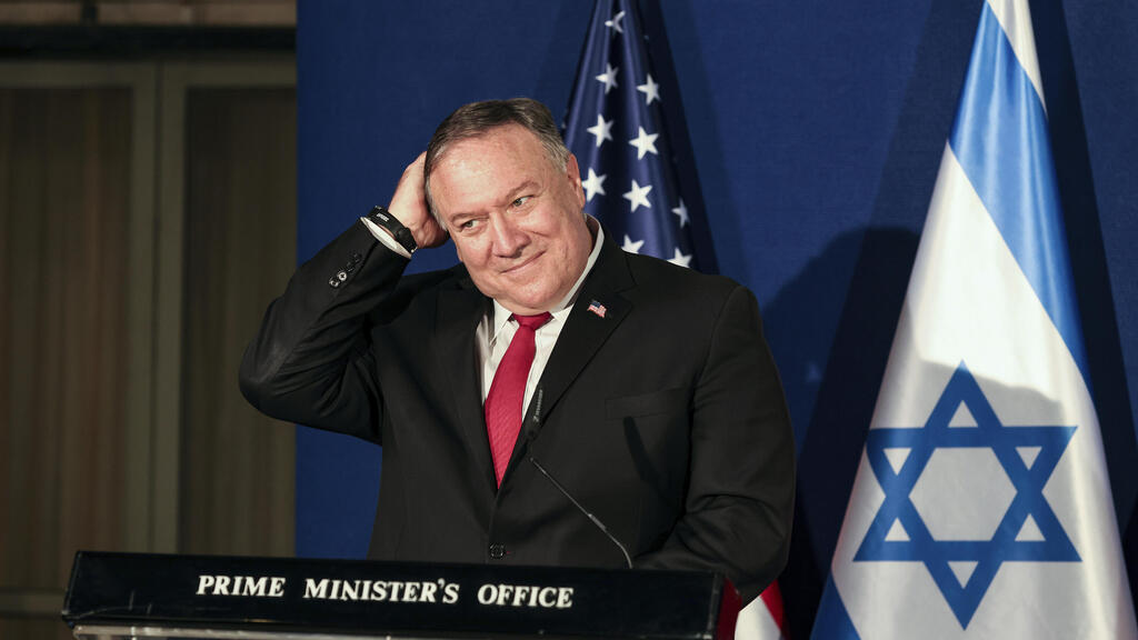 U.S. Secretary of State Mike Pompeo smiles while patting his head during a press conference with Israeli Prime Minister Benjamin Netanyahu