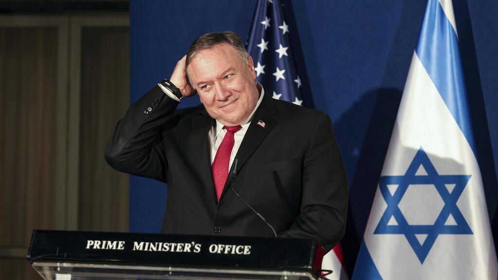 U.S. Secretary of State Mike Pompeo smiles while patting his head during a press conference with Israeli Prime Minister Benjamin Netanyahu