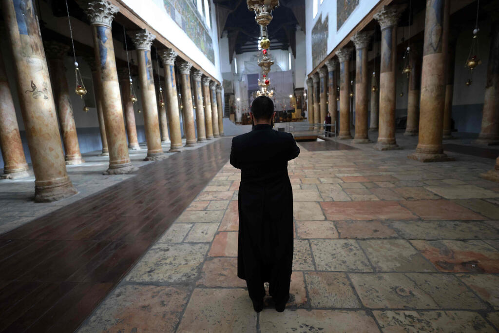 A priest stands inside the deserted Church of the Nativity in the occupied West Bank town of Bethlehem 