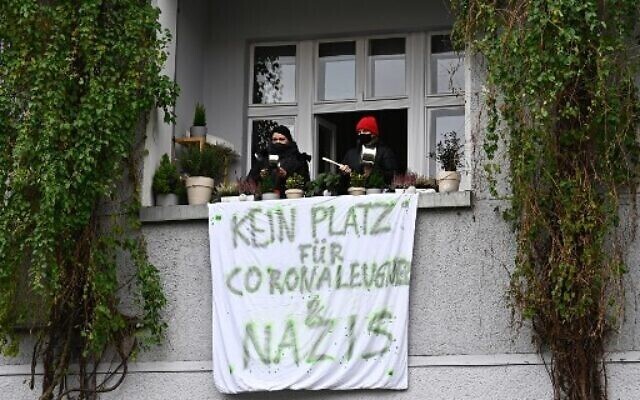 Counter-protesters make noise from their balcony where a banner reading ‘No place for Corona deniers and Nazis’ is fixed during a silent march against measures to curb the spread of the coronavirus in Berlin 